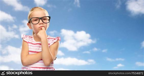education, school and vision concept - cute little girl in black glasses over blue sky and clouds background. girl in glasses thinking over sky background