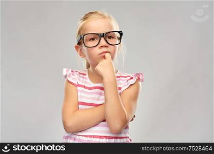education, school and vision concept - cute little girl in black glasses over grey background. cute little girl in black glasses thinking