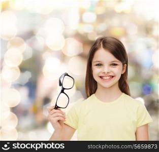 education, school and vision concept - smiling cute little girl holding black eyeglasses
