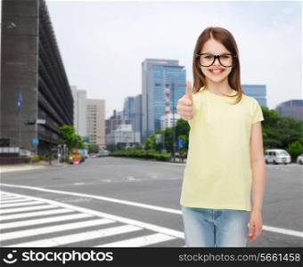 education, school and vision concept - smiling cute little girl in black eyeglasses showing thumbs up
