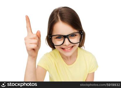 education, school and vision concept - smiling little student girl in eyeglasses pointing finger up