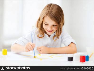 education, school, art and painitng concept - little student girl painting at school