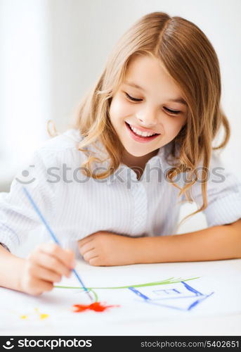 education, school, art and painitng concept - little student girl painting at school