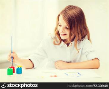 education, school, art and painitng concept - little student girl painting at school