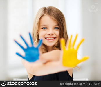 education, school, art and painitng concept - little student girl showing painted hands at school