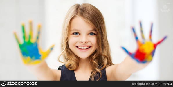 education, school, art and painitng concept - little student girl showing painted hands at school