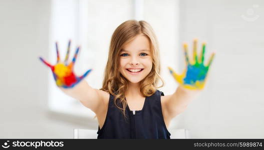 education, school, art and painitng concept - little student girl showing painted hands at school