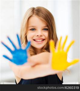 education, school, art and painitng concept - little student girl showing painted hands at school