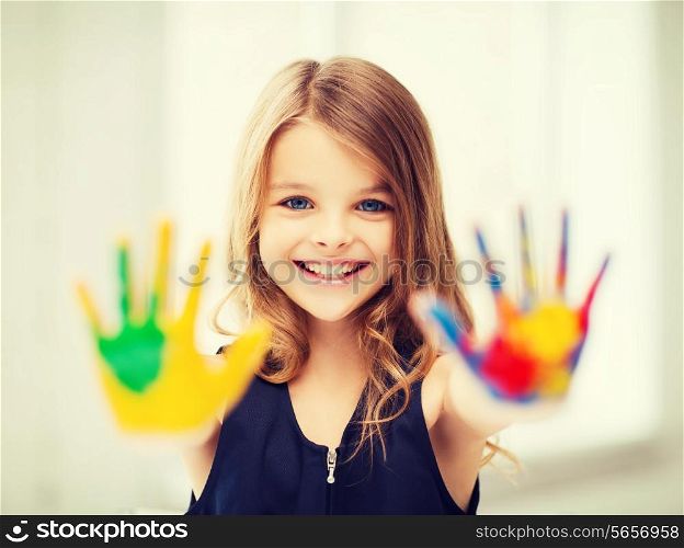 education, school, art and painitng concept - smiling little student girl showing painted hands at school