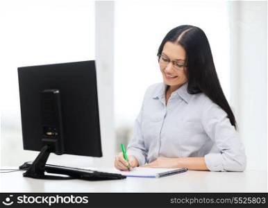 education, school, business and technology concept - smiling businesswoman or student in black eyeglasses making notes