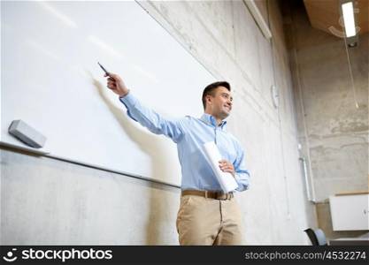 education, school, business, teaching and people concept - happy teacher or businessman pointing marker to white board at lecture