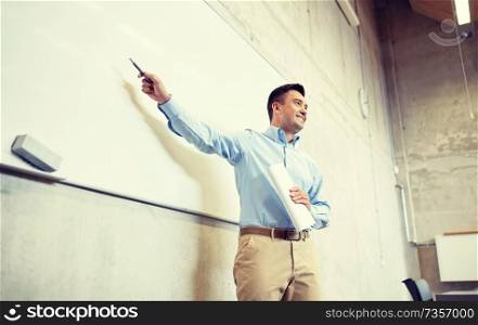 education, school, business, teaching and people concept - happy teacher or businessman pointing marker to white board at lecture. teacher pointing marker to white board at lecture