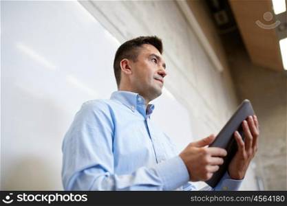 education, school, business, technology and people concept - teacher or businessman with tablet pc computer standing at white board at lecture hall