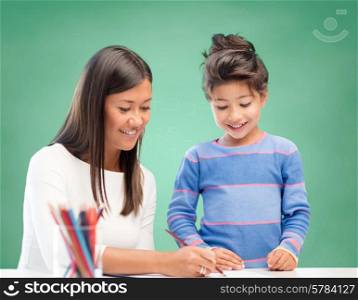 education, school, children, creativity and happy people concept - happy teacher and girl drawing over green chalk board background