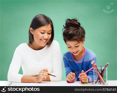 education, school, children, creativity and happy people concept - happy teacher and girl drawing over green chalk board background