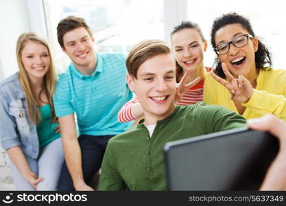 education, school, friendship and technology concept - smiling students making selfie with tablet pc at school