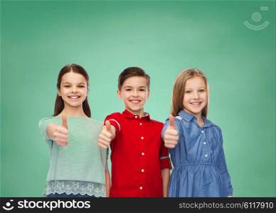 education, school, friendship, gesture and people concept - happy smiling children showing thumbs up over green chalk board background