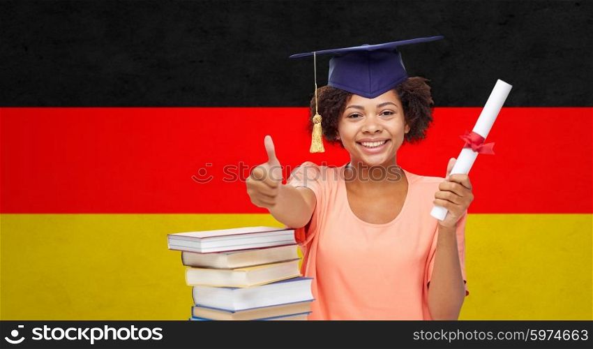 education, school, graduation, gesture and people concept - happy smiling african american student girl in bachelor cap with books and diploma showing thumbs up over german flag background