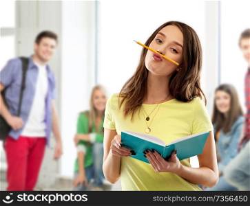education, school, inspiration and people concept - teenage student girl in yellow t-shirt with diary or notebook and pencil-mustache over grey background. teenage student girl with notebook and pencil