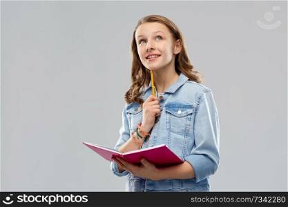 education, school, inspiration and people concept - young woman or teenage student girl in denim jacket with diary or notebook and pencil thinking over grey background. teenage student girl with diary or notebook
