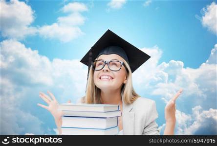 education, school, knowledge, graduation and people concept - happy student girl in bachelor cap with books over blue sky and clouds background