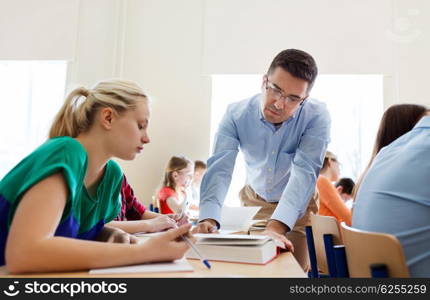 education, school, learning, teaching and people concept - group of students and teacher talking in classroom