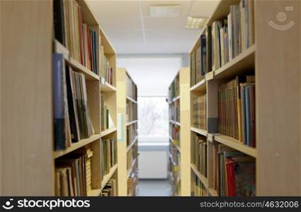 education, school, literature and knowledge concept - bookshelves with books at public library