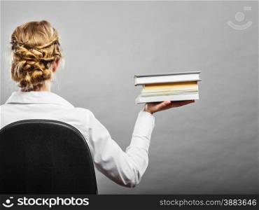 Education school or business concept. Woman female student sitting on chair holding stack books. Back view grunge background