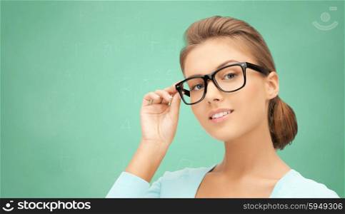 education, school, people and vision concept - happy teenage student girl or woman in eyeglasses over green school chalk board background