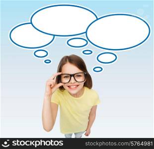 education, school, people, childhood and vision concept - smiling cute little girl in black eyeglasses over blue background with white blank text bubbles