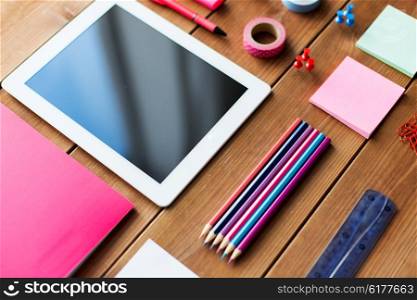 education, school supplies, art, creativity and object concept - close up of stationery and tablet pc computer on wooden table