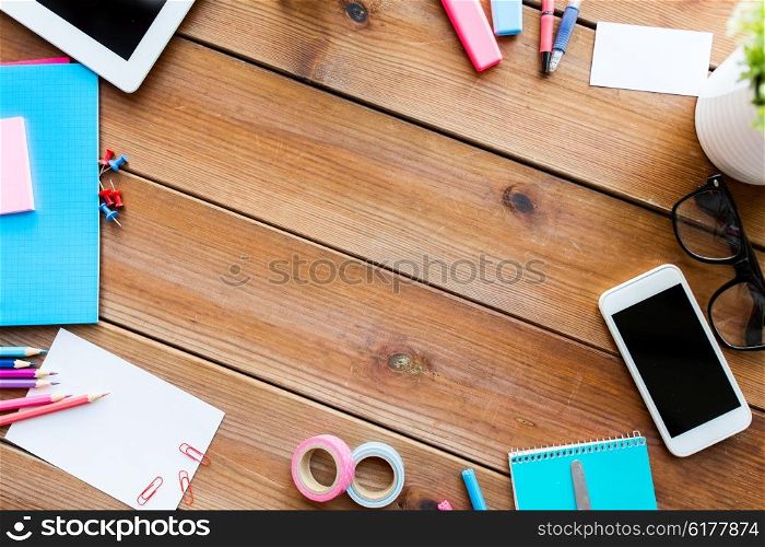 education, school supplies, art, creativity and object concept - close up of stationery and smartphone on wooden table