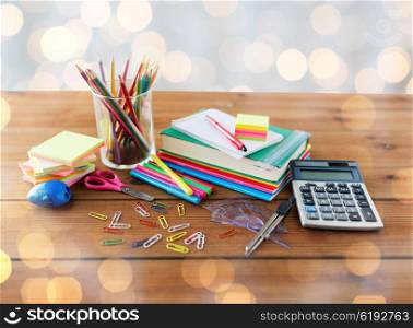 education, school supplies, art, creativity and object concept - close up of stationery on wooden table over holidays lights background