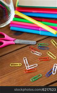 education, school supplies, art, creativity and object concept - close up of felt pens with clips and scissors on wooden table