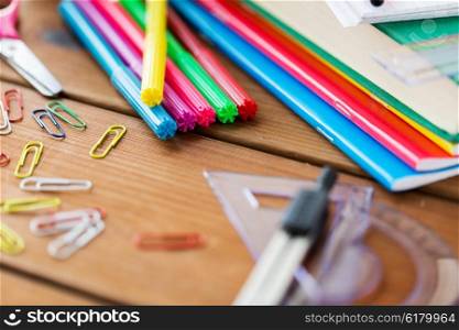 education, school supplies, stationery and object concept - close up of felt pens with clips, notebooks and rulers on wooden table
