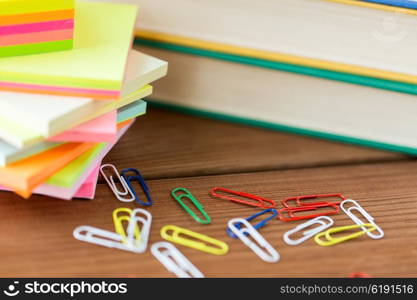 education, school supplies, stationery and object concept - close up of stand or glass with writing tools and book with scissors on wooden table