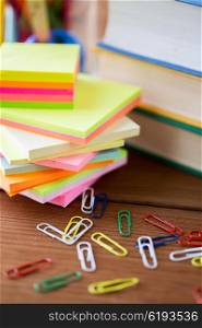 education, school supplies, stationery and object concept - close up of stand or glass with writing tools and book with scissors on wooden table