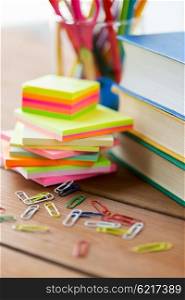 education, school supplies, stationery and object concept - close up of stand or glass with writing tools and book with scissors on wooden table