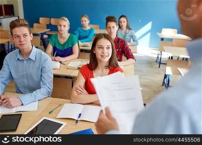 education, school, teaching, learning and people concept - group of happy students and teacher with papers or tests
