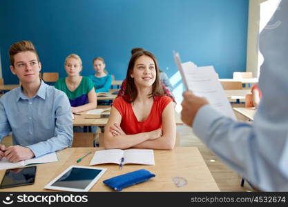 education, school, teaching, learning and people concept - group of happy students and teacher with papers or tests