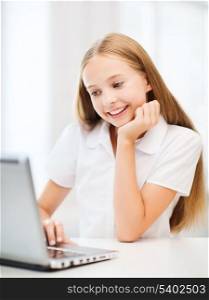 education, school, technology and internet concept - little student girl with laptop pc at school