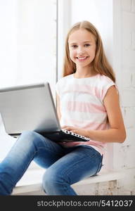 education, school, technology and internet concept - little student girl with laptop pc at school