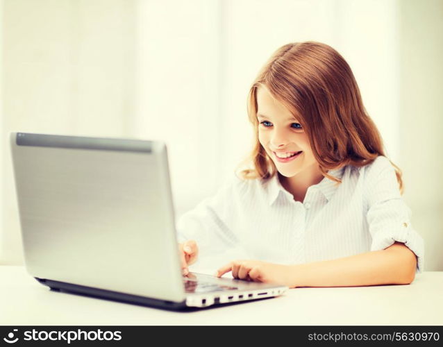 education, school, technology and internet concept - little student girl with laptop pc at school