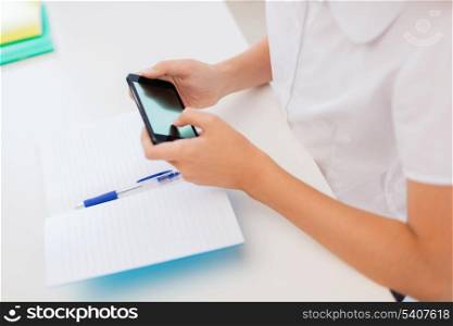 education, school, technology and internet concept - little student girl with notebooks and smartphone at school