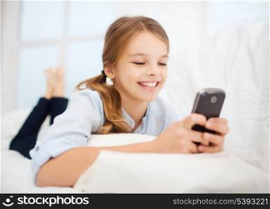 education, school, technology and internet concept - little student girl with smartphone at home