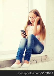 education, school, technology and internet concept - little student girl with smartphone at school