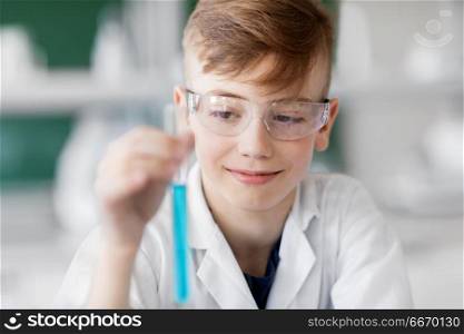education, science and children concept - boy in goggles with test tube studying chemistry at school laboratory. boy with test tube studying chemistry at school. boy with test tube studying chemistry at school