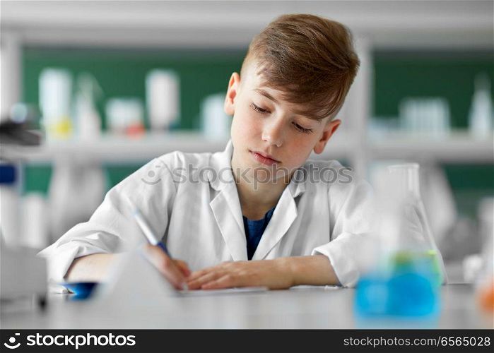 education, science and children concept - boy with notebook studying biology at school. boy with notebook studying biology at school