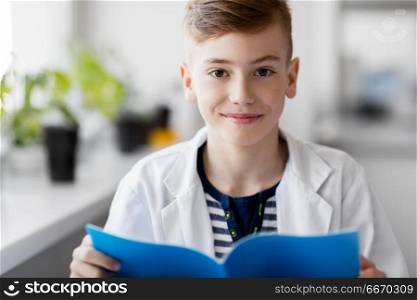education, science and children concept - boy with notebook studying biology at school. boy with notebook studying biology at school. boy with notebook studying biology at school