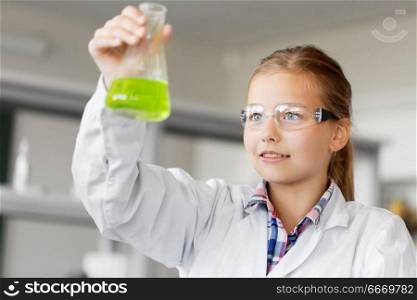 education, science and children concept - girl in goggles with test tube studying chemistry at school laboratory. girl with test tube studying chemistry at school. girl with test tube studying chemistry at school